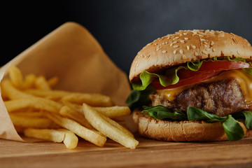 delicious burger with meat and french fries on wooden surface