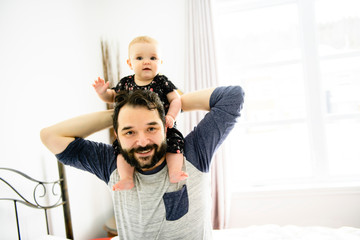 Young happy father playing with baby on bed