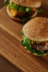 selective focus of tasty meat burgers on wooden chopping board