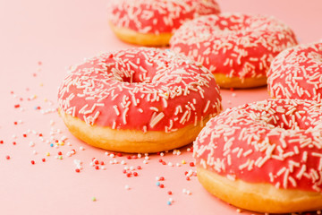 Obraz na płótnie Canvas Coral donuts. Donuts decorated with icing on pink background.
