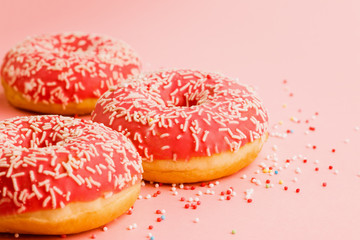 Coral donuts. Donuts decorated with icing on pink background.