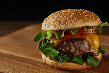close up of tasty meat burger on wooden chopping board