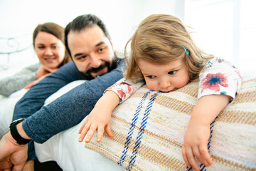 A Happy family, mother, father and daughter on the white bed