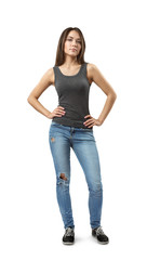 Front view of young beautiful woman in gray sleeveless top and blue jeans standing looking at camera with hands on hips isolated on white background.
