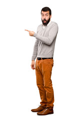 Handsome man surprised and pointing side over isolated white background