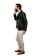 Fototapeta premium Handsome man with beard shouting with mouth wide open to the lateral over isolated white background