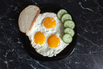 Breakfast. Fried eggs with bread and cucumbers