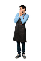 Full-length shot of Man with apron nervous and scared putting hands to mouth over isolated white background