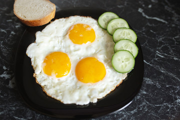 Breakfast. Fried eggs with bread and cucumbers
