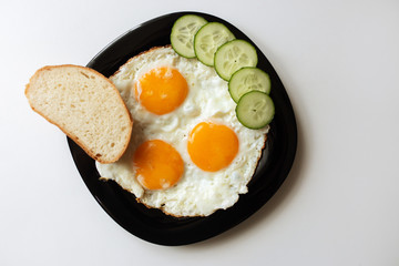 Breakfast. Fried eggs with bread and cucumbers