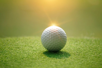 Golf ball on tee in beautiful golf course at sunset background.