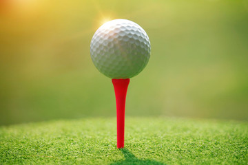 Golf ball on tee in beautiful golf course at sunset background.