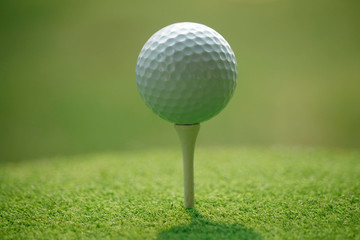 Golf ball on tee in beautiful golf course at sunset background.