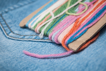 Fototapeta premium closeup of colorful woolen threads on blue jeans background