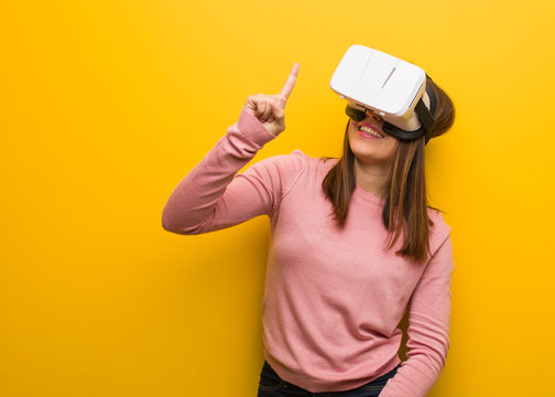 Young cute woman wearing a virtual reality googles showing number one