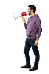 Full-length shot of Handsome man with sweatshirt shouting through a megaphone over isolated white background