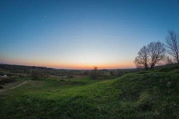 Obraz premium Colorful sunset from the top of a green hill