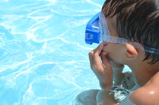 Teenager boy wearing mask swimming in the pool. Happy holiday concept. Cute happy little boy swimming and snorking in the sea ocean in crystal blue water
