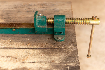 Workpiece clamp, Metal table vise clamp on the wood table. Copy space for text.