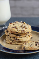 Healthy treat of dried cherry cookies on a plate with a glass of milk sitting on a blue countertop. Cherries have antioxidants, and are Anti-Inflammatory