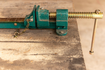 Workpiece clamp, Metal table vise clamp on the wood table. Copy space for text.