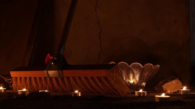 Alter Besen steht in einem verlassenen Stall inmitten von Kerzenschein und flackernden Lichtern