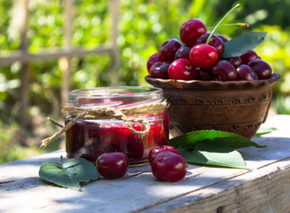 cherry jam in glass and ripe fresh cherries on natural
