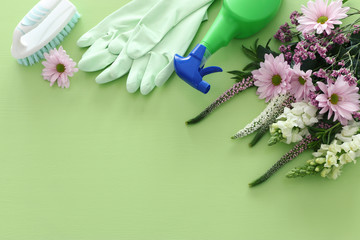 Spring cleaning concept with supplies over pastel green wooden background. Top view, flat lay