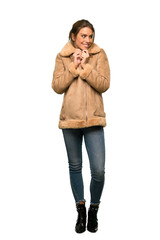 A full-length shot of a Blonde woman with a coat scheming something over isolated white background