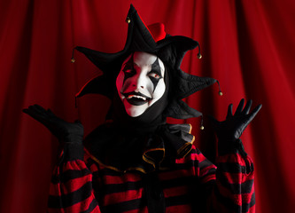 Cute cheerful and surprised jester showing performance on the stage. - obrazy, fototapety, plakaty