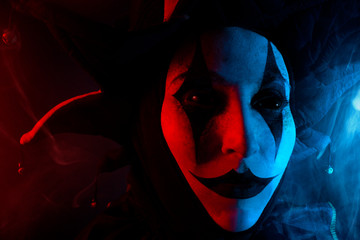 Creepy jester's face with black eyes, close-up.