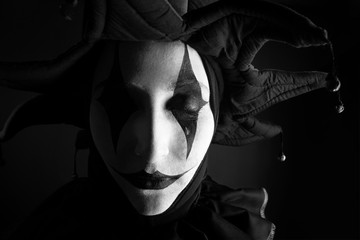 Sad crying jester, black and white photo, close-up.
