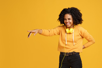 Charming african american young woman with bright smile dressed in casual clothes and headphones...
