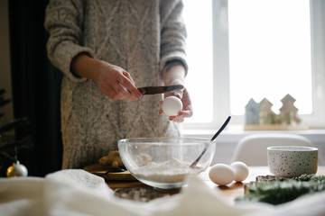 woman breaks an egg and adds to the flour. Process Cooking.