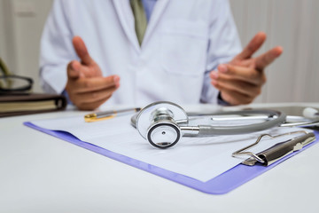 Close-up of stethoscope is lying on the clipboard in front of  a doctor.