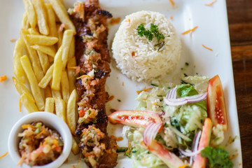 grilled pork meat served on plate with french fries, rice and vegetables