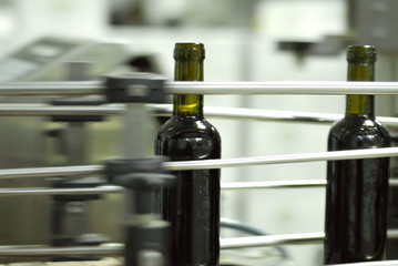 Red wine bottling and sealing conveyor line at winery factory. Blurred image as an artistic effect.