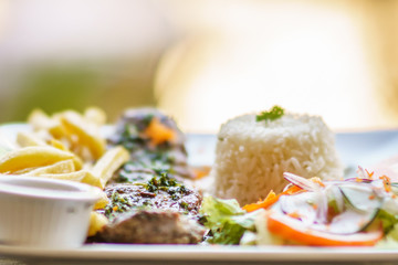 grilled beef steak served on plate withh rice, salad and frites. Selective focus photography