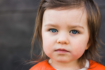 Child Toddler Portrait Closeup. Beautiful Baby Girl with Blue Eyes Looks Seriously