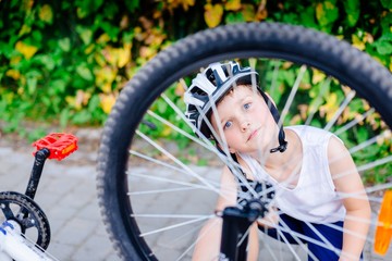 Fototapeta na wymiar Happy little child boy in white helmet repairing his bicycle