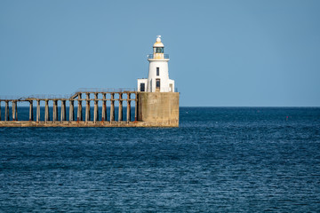 Blyth Lighthouse and the pier on the North Sea Coast, seen on South Beach in Blyth, England, UK