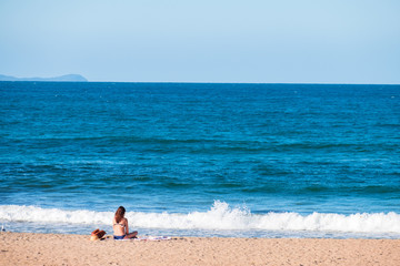 Fototapeta na wymiar A bikini girl doing meditation and enjoying next to the ocean. Peaceful concept.