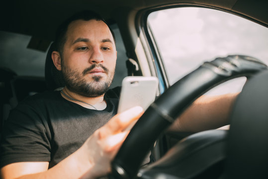 a man driving a car distracted by a smartphone