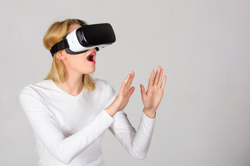 Woman wearing virtual reality goggles. Person with virtual reality helmet isolated on grey background. Woman with virtual reality headset. VR gaming.
