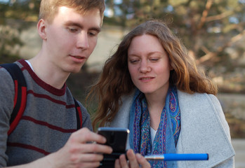 mobile photo: a young man shows a girl her pictures on the phone