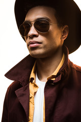 Obraz premium stylish mixed race man in sunglasses and hat posing isolated on white