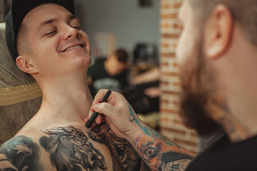 Cropped shot of a cheerful handsome man smiling, preparing to get a new tattoo. Rear view shot of a...