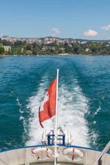 Passenger boat with Swiss flag leaving Lausanne port of Ouchy on Lake Leman (Geneva Lake), Switzerland on beautiful summer sunny day