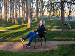 A senior woman with white hair practicing gymnastics in a bio-healthy park