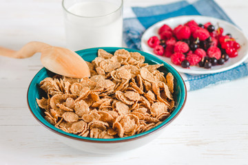 Breakfast cereal with milk on a white background. Flakes on a plate. Muesli with berries and milk